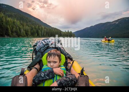 Kleiner Junge mit mürrem Gesicht auf einem See während des Paddelns Reise Stockfoto