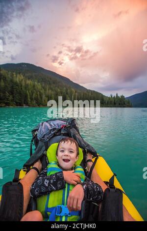 Kleiner Junge lächelt, lacht während Vater Sohn Paddeltour. Stockfoto