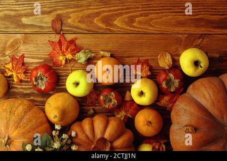 Herbstkomposition mit Kürbissen, Kaki, Äpfeln und herbstgelben Blättern. Reife Kürbisse auf einem hölzernen Plankentisch. Draufsicht mit Kopierbereich. Flach mit Gemüse und Obst legen. Stockfoto