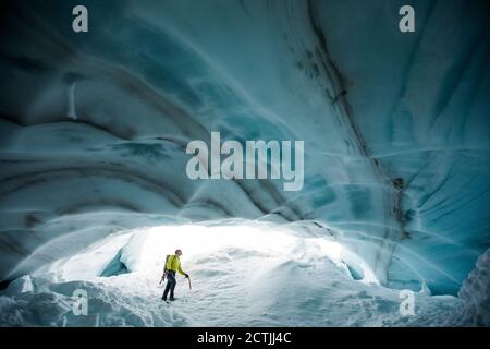 Der Eiskletterer blickt an die Decke einer Gletscherhöhle in Kanada. Stockfoto