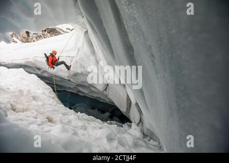 Der Bergsteiger rappelt in die Gletscherspalte, um nach verlorenen Wanderern zu suchen Stockfoto