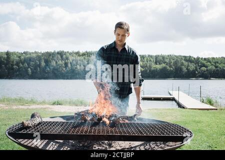 Mann, der draußen am Strand in Schweden ein bbq macht Stockfoto