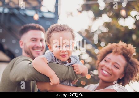 Schwarz Mama und weiß Papa hält Baby junge und spielen Flugzeug Stockfoto