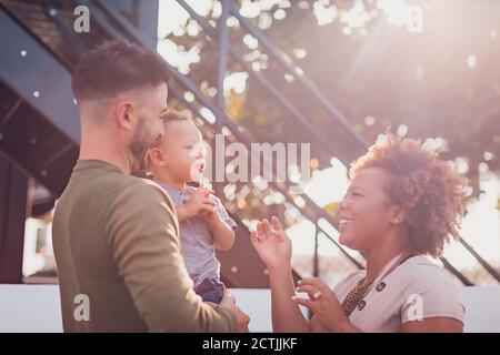 Papa hält Baby und Mama spielt mit ihm Stockfoto