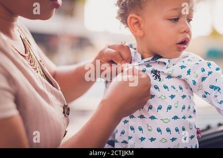 Mama buttoning Baby Jungen Shirt, nah an Händen und Jungen Gesicht.