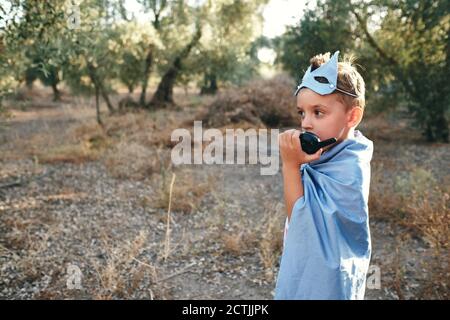 Kind verkleidet als blauer Superheld nimmt das Walkie Talkie Um zu bitten Stockfoto