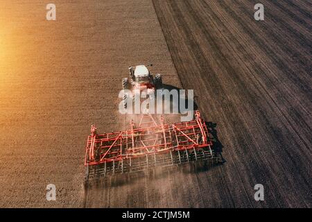 Traktor Anbau oder Pflügen Ackerfeld in Sonnenuntergang Licht, Luftaufnahme. Stockfoto