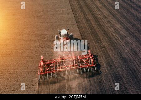 Traktor Anbau oder Pflügen Ackerfeld in Sonnenuntergang Licht, Luftaufnahme. Stockfoto