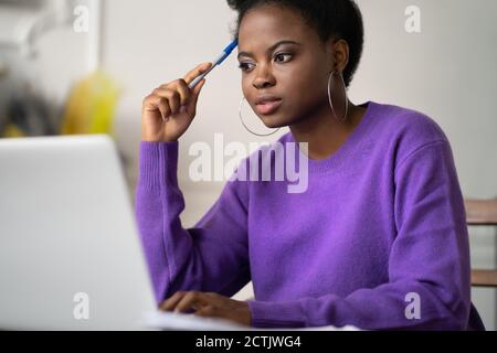 Afro-amerikanische Millennial Student Frau mit afro Frisur Browsing Informationen auf Laptop, Vorbereitung für die Prüfung online, Video-Kurs, halten eine Stockfoto