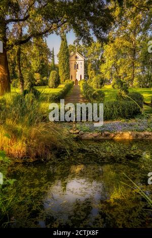 Blick auf einen Teich mit Wasserpflanzen am Fuße eines Hügels im Parco Giardino Sigurtà in Valeggio sul Mincio bei Verona (Italien). Stockfoto