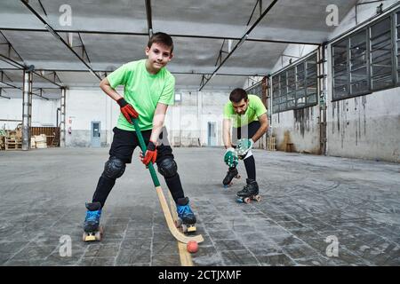 Reifer Mann mit Sohn üben Roller Hockey auf dem Platz Stockfoto