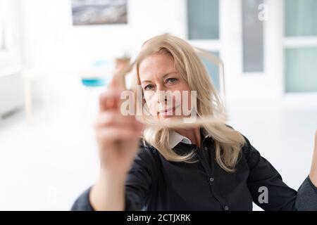 Nahaufnahme einer selbstbewussten Geschäftsfrau, die im Heimbüro durch das Modell schaut Stockfoto