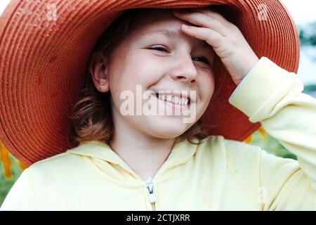 Lächelndes Mädchen trägt Sonnenhut im Feld im Sommer Stockfoto