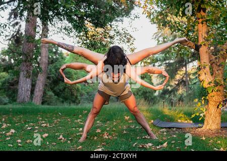 Mann balanciert Frau auf dem Rücken, während acroyoga im Park praktiziert Stockfoto