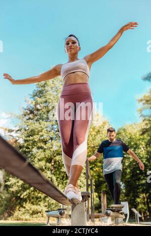 Frau balanciert auf Slackline auf einem Fitness-Parcours Stockfoto