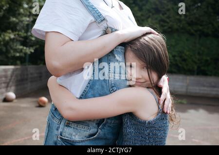 Tochter und Mutter umarmen sich im Hinterhof Stockfoto