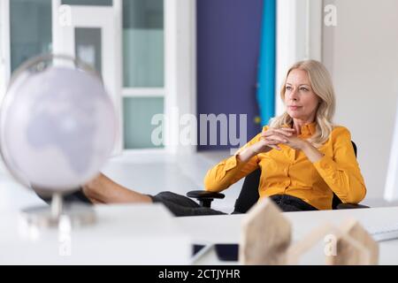 Nachdenkliche Geschäftsfrau mit Händen geklammert sitzen auf einem Stuhl in zu Hause Büro Stockfoto