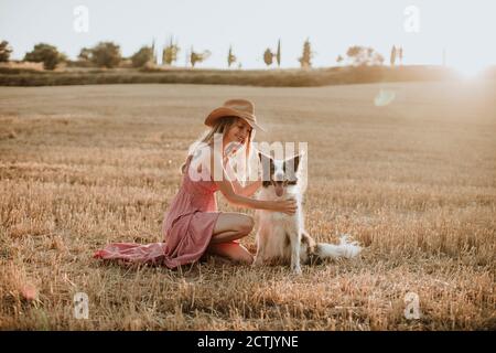 Frau genießen mit Border Collie Hund im Weizenfeld während Sonnenuntergang Stockfoto