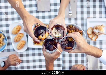 Die Hände der Freunde toasten Wermut am Tisch im Café Stockfoto