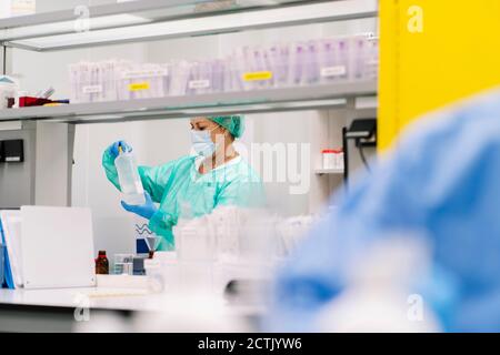 Wissenschaftlerin hält Flasche, während sie im Labor im Krankenhaus steht Stockfoto