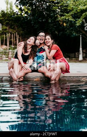 Glückliche Freunde, die am Pool sitzen Stockfoto