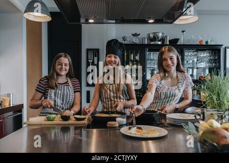 Freundinnen bereiten gemeinsam gesundes Mittagessen zu, braten Eier in der Küche Stockfoto