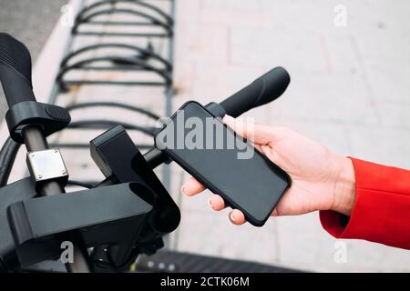 Hand der weiblichen professionellen Scannen QR-Code auf elektrischen Push Roller von Smartphone Stockfoto