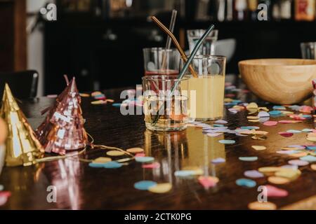 Nahaufnahme von Getränken mit Partyhüten und Konfetti beim Abendessen Tisch zu Hause Stockfoto