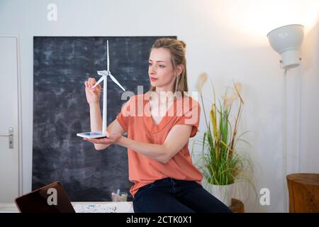 Frau im Büro mit Windturbinenmodell Stockfoto