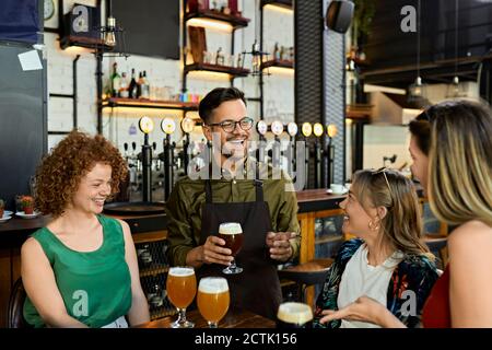 Kellner serviert Craft Beer für weibliche Freunde in einem Pub Stockfoto