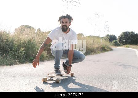 Schöner bärtiger reifer Mann Skateboarding auf der Straße gegen klaren Himmel Stockfoto