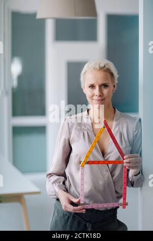 Selbstbewusste weibliche Architektin hält Modell, während im Büro stehen Stockfoto