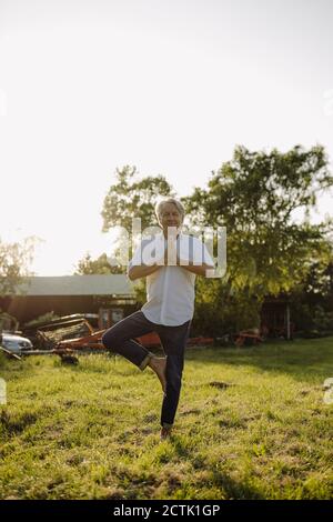 Mann, der Yoga auf einem Bein gegen klaren Himmel macht Hof Stockfoto