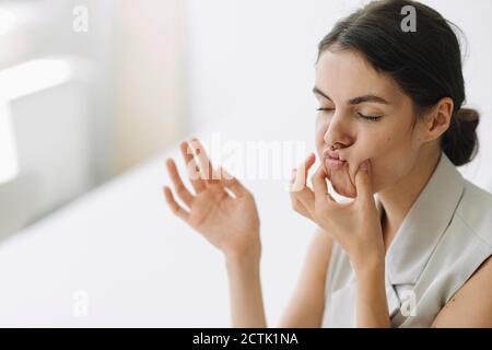 Verspielte Frau macht Gesichter, während im Büro sitzen Stockfoto