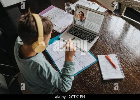 Schuljunge zu Hause lernen, mit Laptop und Kopfhörer Stockfoto