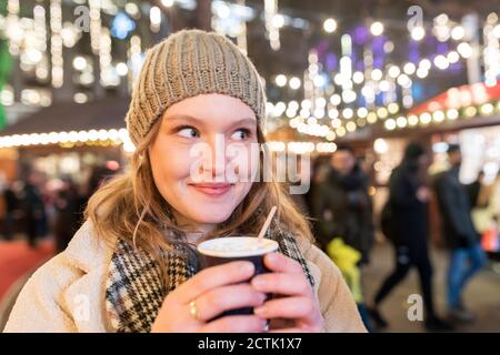 Nahaufnahme der schönen Frau mit heißer Schokolade auf dem Weihnachtsmarkt Nachts Stockfoto