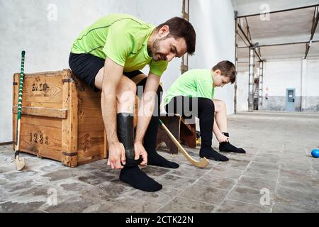 Reifer Mann und Sohn tragen Socken, während sie auf Holz sitzen Box auf dem Platz Stockfoto