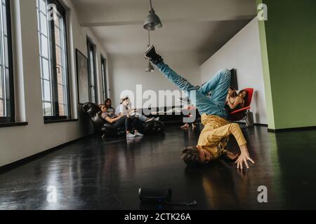 Freunde, die Jungen beim Breakdance auf dem Boden betrachten Stockfoto