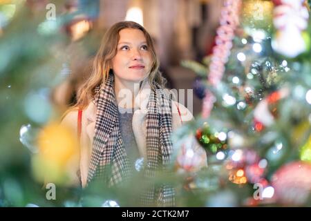 Junge Frau schaut auf beleuchteten Weihnachtsbaum und Lichter in Stadt Stockfoto