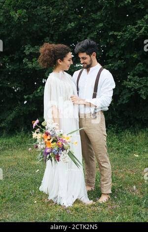 Mann, der Braut Hochzeitskleid beim Stehen im Garten Stockfoto