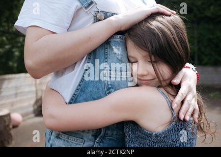 Mädchen umarmt Mutter auf Hinterhof an sonnigen Tag Stockfoto