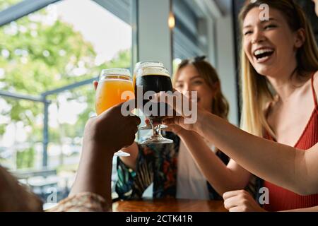 Glückliche Freundinnen klirren Craft Biergläser in einem Pub Stockfoto