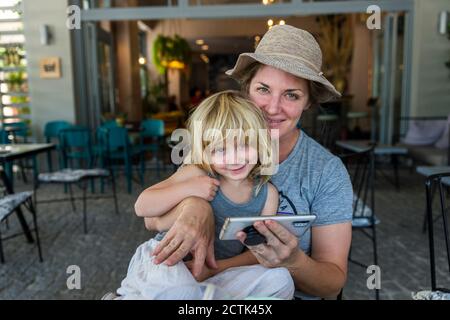 Portrait von Mutter und Tochter sitzen zusammen im Freien mit smart Telefon Stockfoto