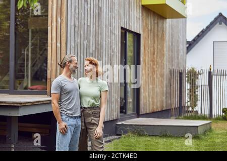 Romantisches Paar, das sich ansieht, während es draußen winzig steht Haus im Hof Stockfoto