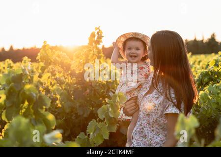 Mutter hält ihre Tochter in einem Weinberg bei Sonnenuntergang in der Provence, Frankreich Stockfoto