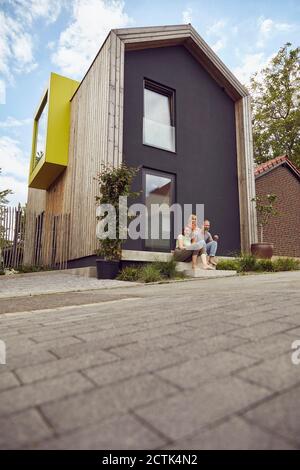 Familie sitzt auf Treppen vor dem winzigen Haus Stockfoto