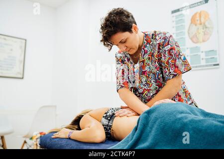 Weibliche Osteopatherapeutin, die der Sportlerin bei der Gesundheit eine Rückenmassage gibt Spa Stockfoto