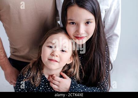 Mädchen umarmt Schwester mit Eltern im Hintergrund im Studio stehen Stockfoto