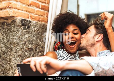 Nahaufnahme des Mannes küssen fröhlich Freundin während der Aufnahme Selfie mit Sie im Café Stockfoto