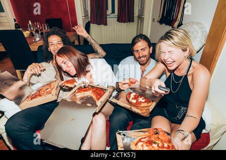Fröhliche Freunde, die während der Party beim Essen Pizza Fernsehen Zu Hause Stockfoto